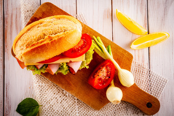 Tasty sandwich with meat and vegetables on wooden table