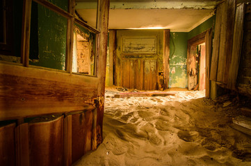 Wooden doors of an abandoned house partly buried in the sand