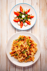 Fusilli with sausages and vegetables on wooden table