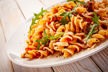 Fusilli with sausages and vegetables on wooden table