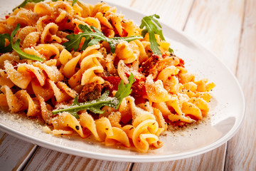 Fusilli with sausages and vegetables on wooden table