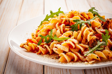 Fusilli with sausages and vegetables on wooden table