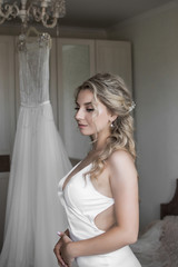 bride on the background of her wedding dress. preparation for the ceremony. wedding day. selective focus. film grain.