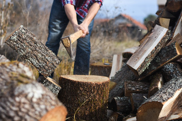 Lumberjack chopping wood for winter, Young man chopping woods with an axe