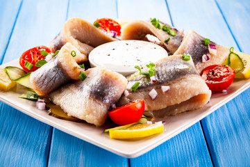 Marinated herring fillets on wooden table