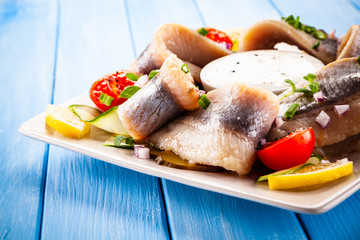Marinated herring fillets on wooden table