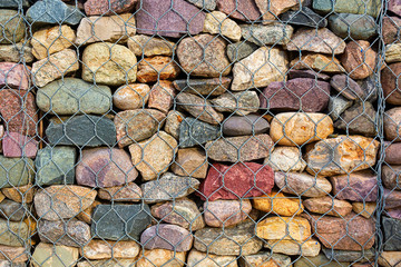Abstract background stones in iron nets protect the beach and shore from wave erosion during storms. strengthening the banks of masonry. Close-up.