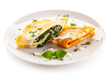 Crepes with spinach and feta cheese on white background