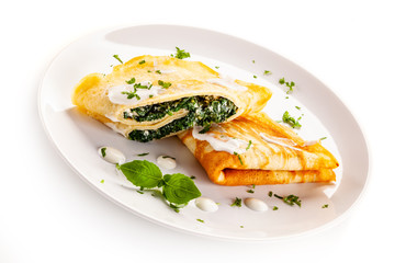 Crepes with spinach and feta cheese on white background
