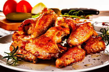 Barbecued chicken wings with french fries and vegetable salad on timber