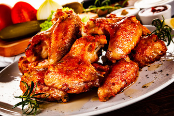 Barbecued chicken wings with french fries and vegetable salad on timber
