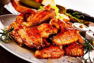 Barbecued chicken wings with french fries and vegetable salad on timber