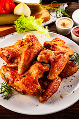 Barbecued chicken wings with french fries and vegetable salad on timber