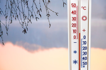 The thermometer on the background of the river in the morning shows 10 degrees of heat_