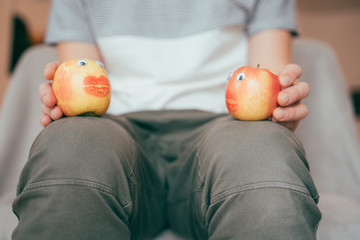 Zwei Äpfel mit Knutschmund spielen ein Theater auf dem Schoß eines Mannes