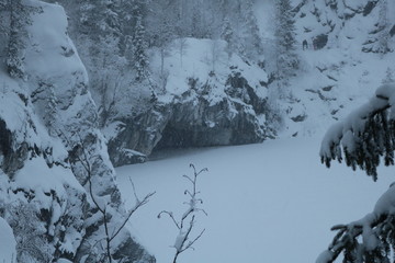 Snow covered rocks with deep grottoes around the frozen lake