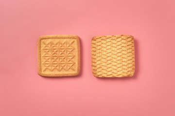 Two whole square cookies lies on pink desk on kitchen. Close-up