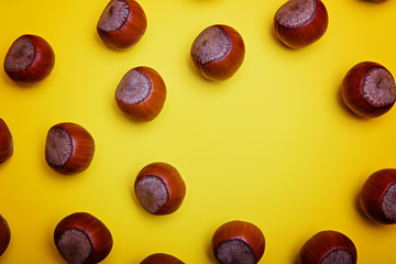 Unpeeled hazelnuts on a yellow background. Flatley. Copy space.