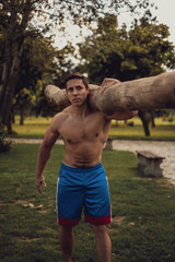Man carrying wood log in an outdoor gym