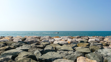 View to the blue see and sky from the rocky beach shot at bright summer day, vacation destination UAE Dubai