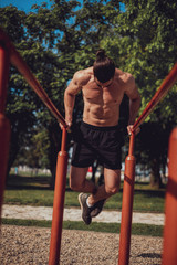 Bearded man doing dips and looking down