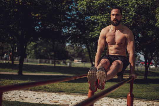 Bearded man doing L sit hold on the bars