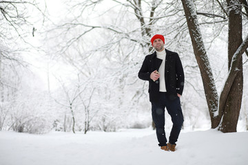 A man on a walk in the park. Young man with in the winter snowfall.