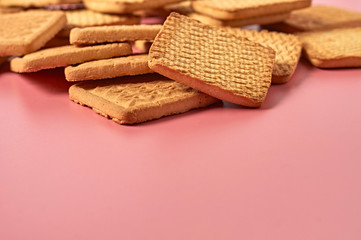 Scattered whole square cookies on pink desk on kitchen. Space for text