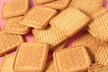 Scattered whole square cookies on pink desk on kitchen. Close-up