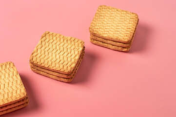 Three heaps of whole square cookies on pink desk on kitchen. Space for text
