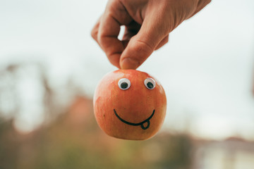 Ein frecher Apfel wird von einer Hand am Stiel gehalten