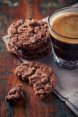Chocolate Cookies with and coffee in glass cup on rustic wooden background. Close up.