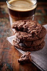 Chocolate Cookies with and coffee in glass cup on rustic wooden background. Close up. 