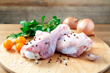 Fresh turkey legs with ingredients for cooking on wooden board 