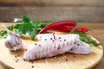 Turkey raw wings on wooden board with vegetables 