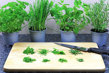Piles Of Freshly Chopped Herbs On A Wooden Chopping Board.