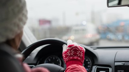 young female driving car in winter Christmas clothes: nice knitted gloves and hat and red jacket - Powered by Adobe