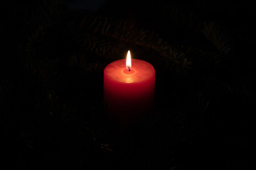 Christmas motif with red burning candle and dark background
