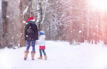 A winter fairy tale in the forest. A girl on a sled with gifts on the eve of the new year in the park. Two sisters walk in a New Year's park and ride a sled with gifts.
