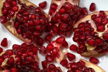 Juicy pomegranate slices on a white plate close-up. Top view.