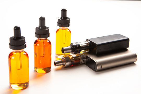 Electronic cigarettes and bottles of yellow liquids. Vaping accessories on a white table. The concept of vaping. Smoking electronic cigarettes. Sale of Smoking accessories. Gadgets for Smoking.