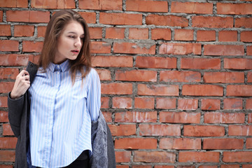 Young beautiful girl near red brick wall posing