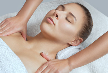 Obraz na płótnie Canvas Masseur makes a relaxing massage on the face, neck, shoulders and collarbones of a young beautiful woman in a spa. Cosmetology and massage concept.