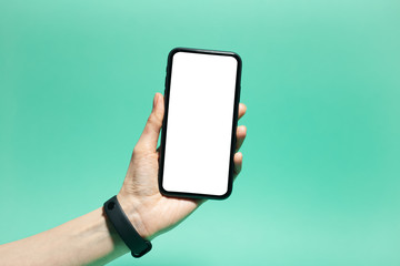 Close-up of female hand holding a smartphone with white mockup on display. Isolated, on color of aqua menthe background.