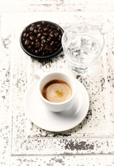 Cup of coffee and coffee beans on bright wooden background. 