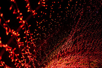 A wave of red LEDs in the dark. Abstract bright red background built on LED strips. City lighting in the park for the New Year holidays. Christmas decoration.