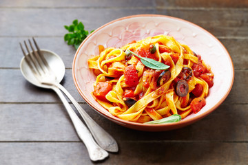 Tagliatelle pasta on brown wooden background.