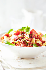  Pappardelle Pasta with cherry tomatoes, red onion and fresh basil on bright background.