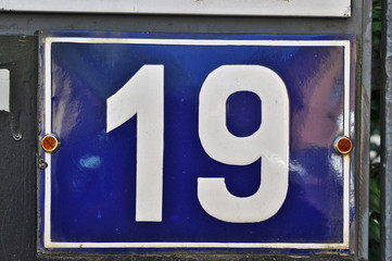 A house number plaque, showing the number nineteen (19)