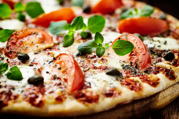 Vegetarian pizza with mozzarella cheese, tomatoes and capers.  Close up. 